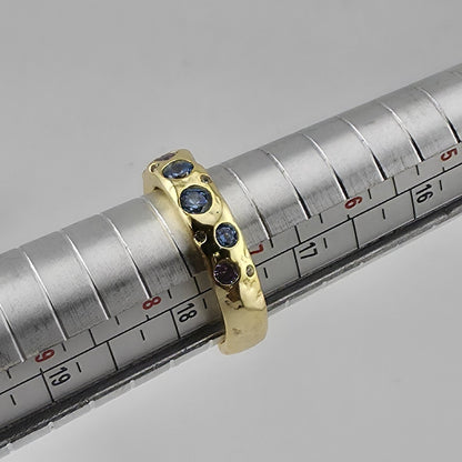 Gold ring with blue gemstones on a metal rod with measurement scale