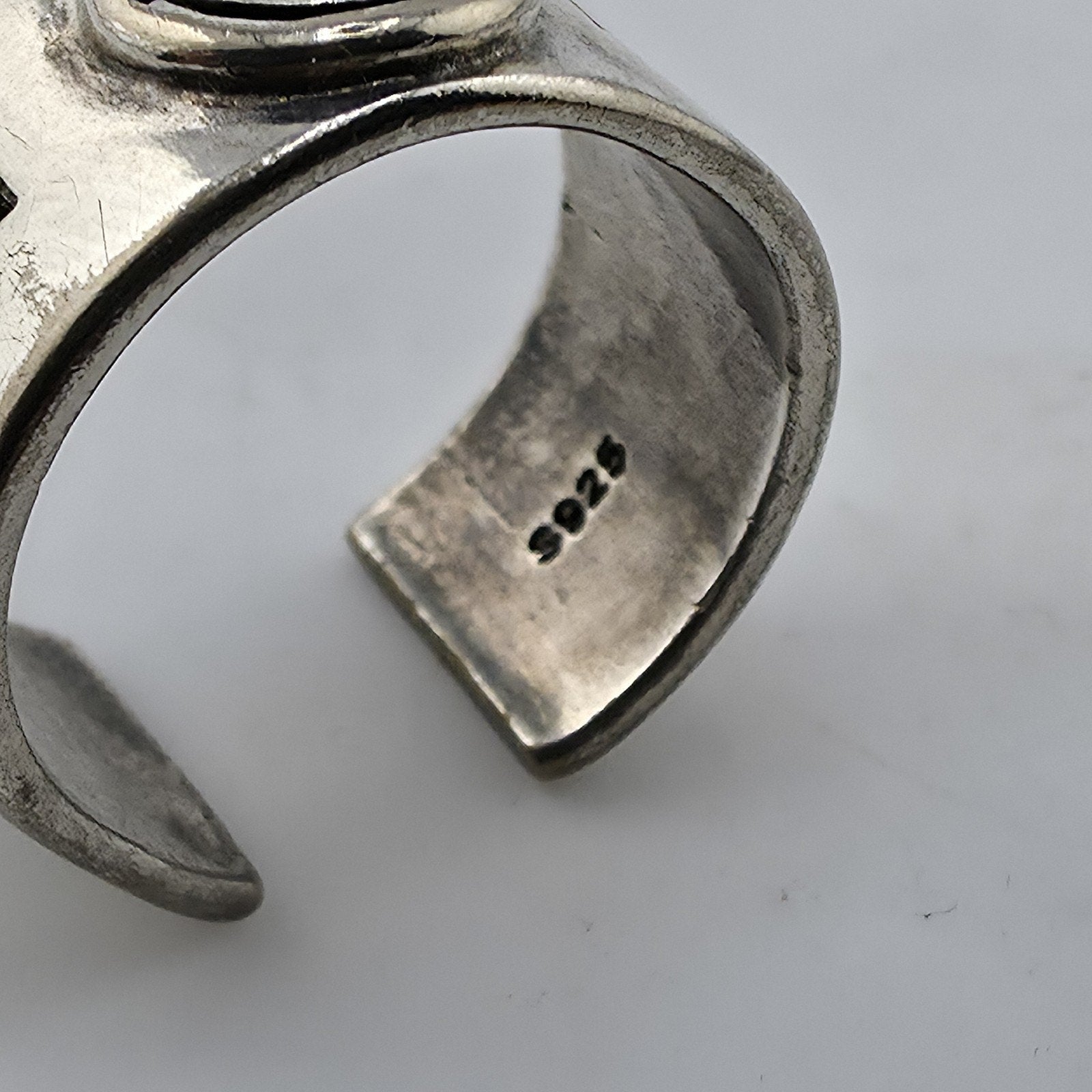 Silver ring with engraved design on a light gray background