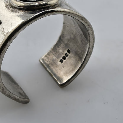 Silver ring with engraved design on a light gray background