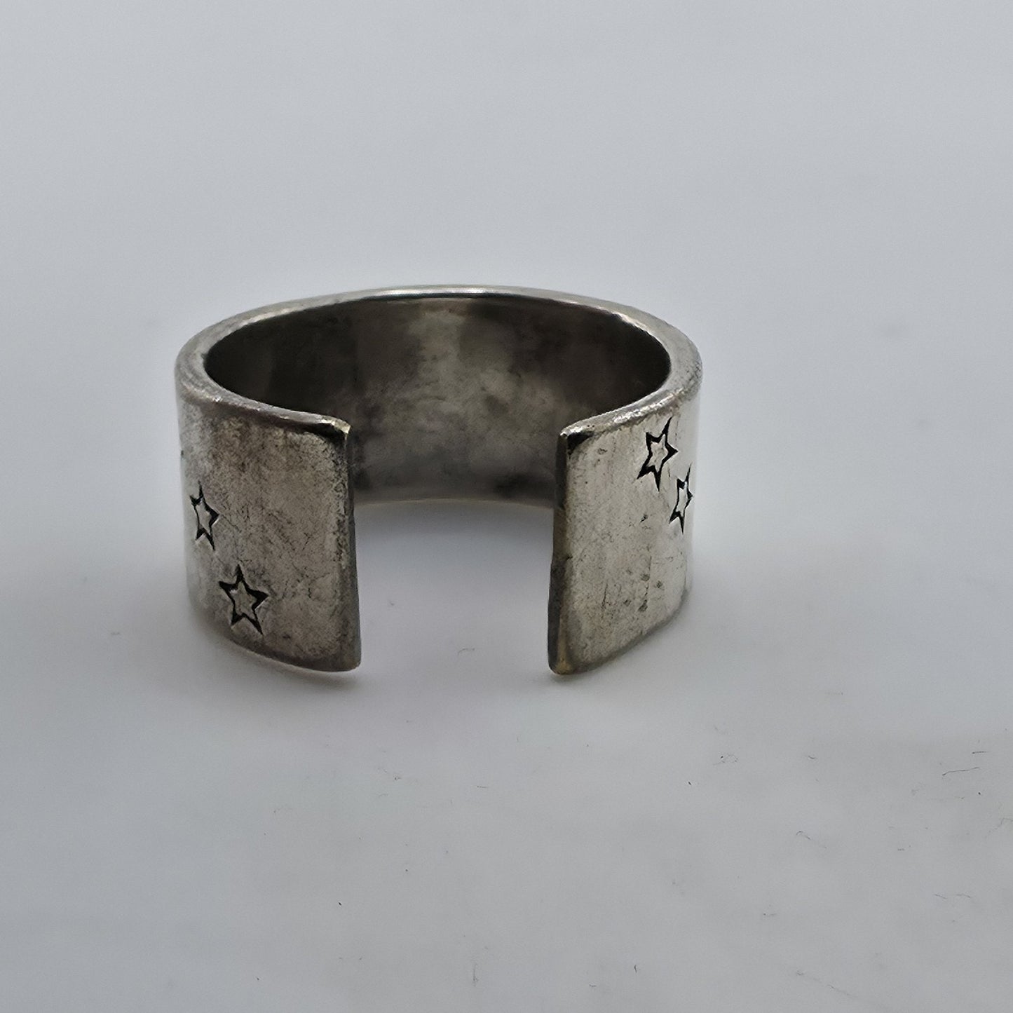 Silver open ring with star designs on a light gray background