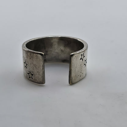 Silver open ring with star designs on a light gray background